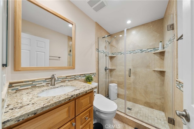 bathroom with vanity, toilet, a shower with shower door, and tile walls