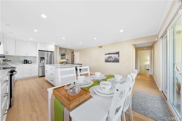 dining space with crown molding and light hardwood / wood-style flooring