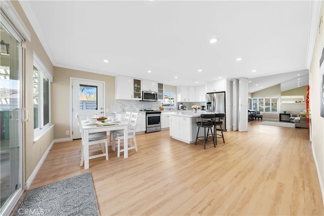 kitchen featuring a breakfast bar, appliances with stainless steel finishes, white cabinetry, a kitchen island, and decorative backsplash