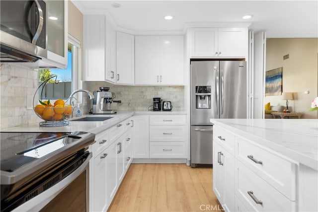 kitchen featuring white cabinetry, appliances with stainless steel finishes, sink, and light stone counters