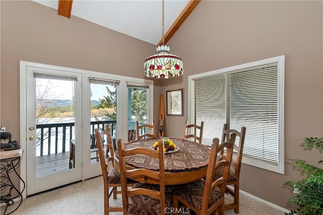 carpeted dining space featuring high vaulted ceiling