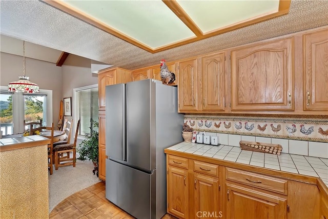 kitchen with stainless steel refrigerator, backsplash, tile counters, and pendant lighting