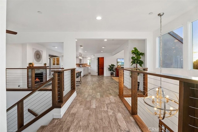 corridor with recessed lighting, wood finished floors, an upstairs landing, and a notable chandelier