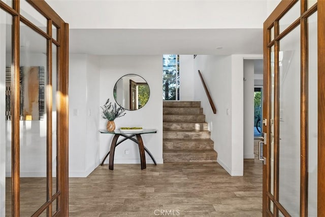 entryway featuring stairway, wood finished floors, and french doors