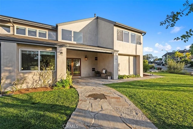 rear view of property with french doors, a lawn, and stucco siding