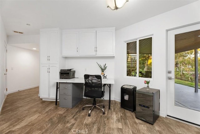 office space featuring visible vents, baseboards, and wood finished floors