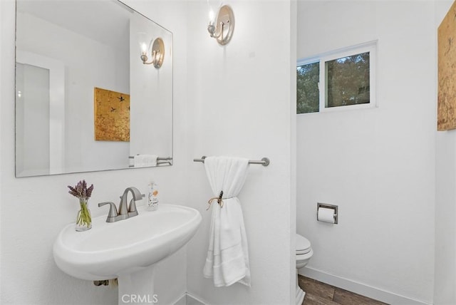 bathroom with baseboards, a sink, toilet, and wood finished floors