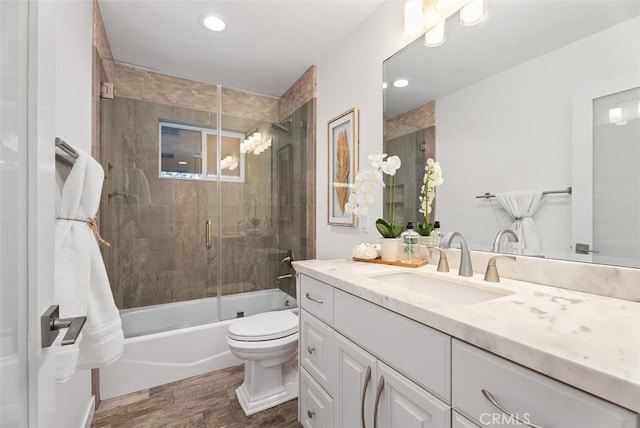 bathroom with toilet, combined bath / shower with glass door, wood finished floors, and vanity