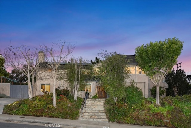 view of property hidden behind natural elements featuring stairs and stucco siding