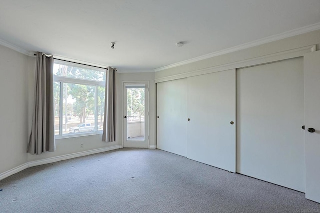 unfurnished bedroom featuring access to exterior, crown molding, light colored carpet, and a closet