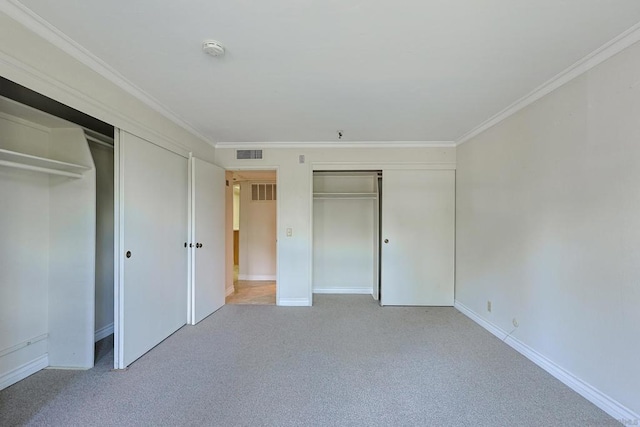 unfurnished bedroom featuring light carpet, crown molding, and multiple closets