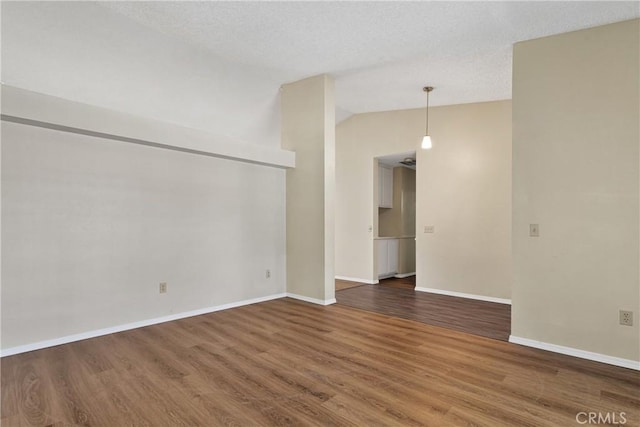 empty room featuring vaulted ceiling and dark wood-type flooring