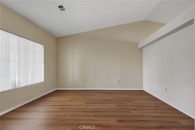 empty room featuring dark wood-type flooring and vaulted ceiling