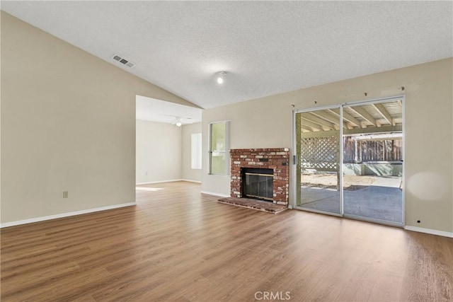 unfurnished living room with plenty of natural light, vaulted ceiling, wood-type flooring, and a textured ceiling