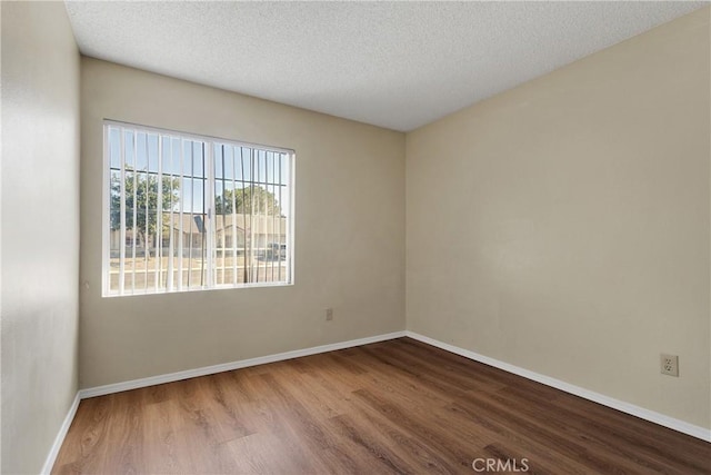 unfurnished room featuring wood-type flooring and a textured ceiling