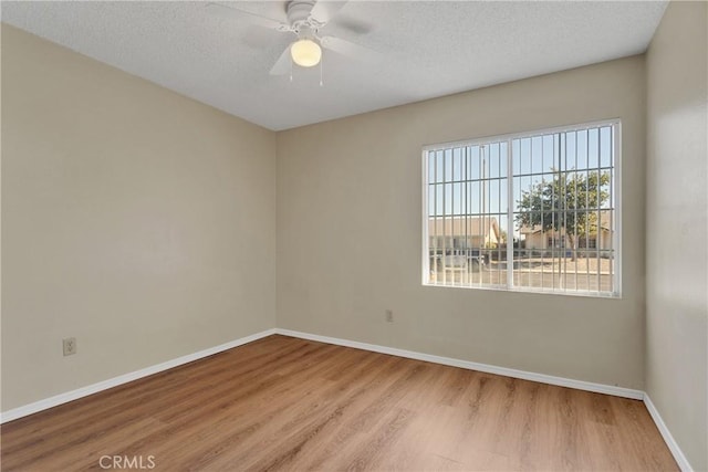 unfurnished room with ceiling fan, a textured ceiling, and light wood-type flooring