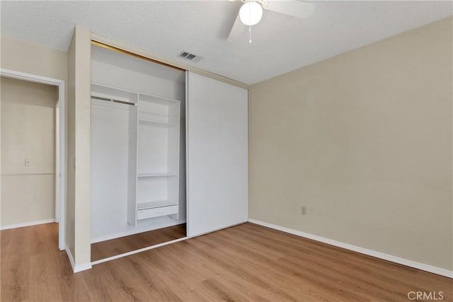 unfurnished bedroom with ceiling fan, wood-type flooring, a closet, and a textured ceiling