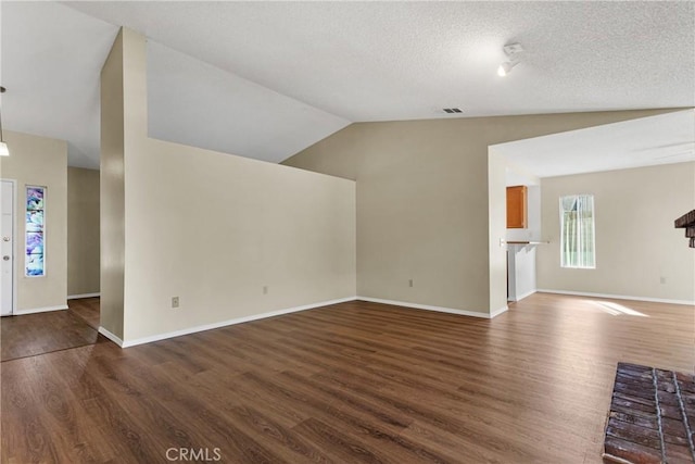 unfurnished living room featuring lofted ceiling, dark hardwood / wood-style floors, and a textured ceiling