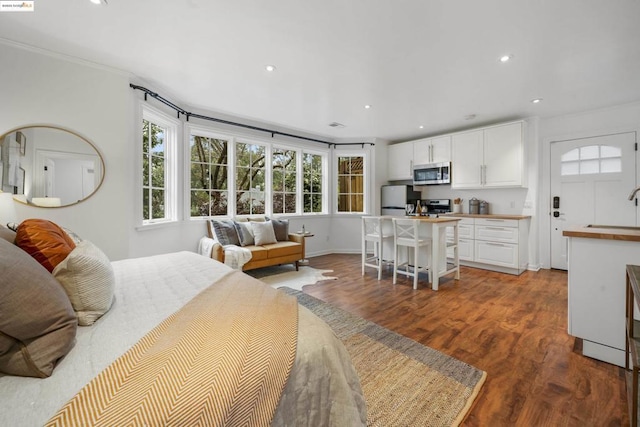 bedroom with ornamental molding, sink, stainless steel fridge, and dark hardwood / wood-style floors