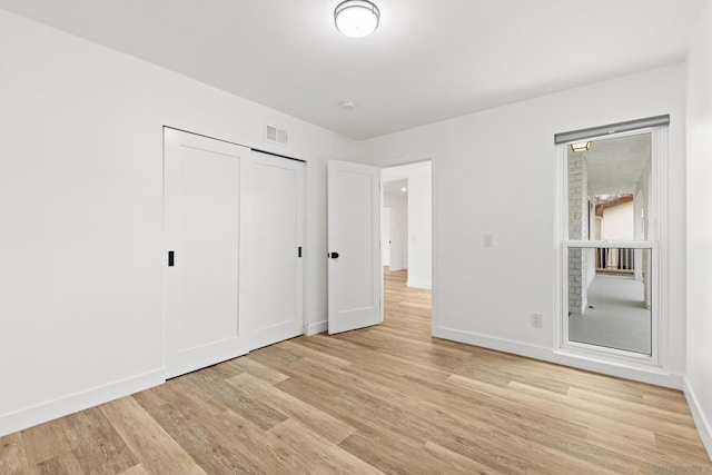 unfurnished bedroom with light wood-type flooring and a closet