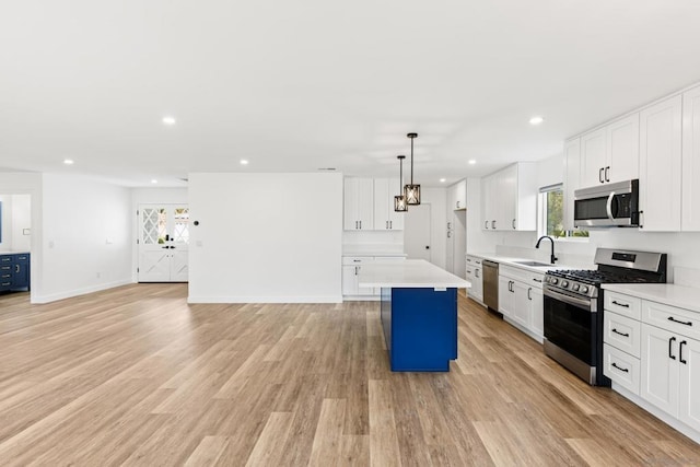 kitchen with decorative light fixtures, stainless steel appliances, a center island, and white cabinets