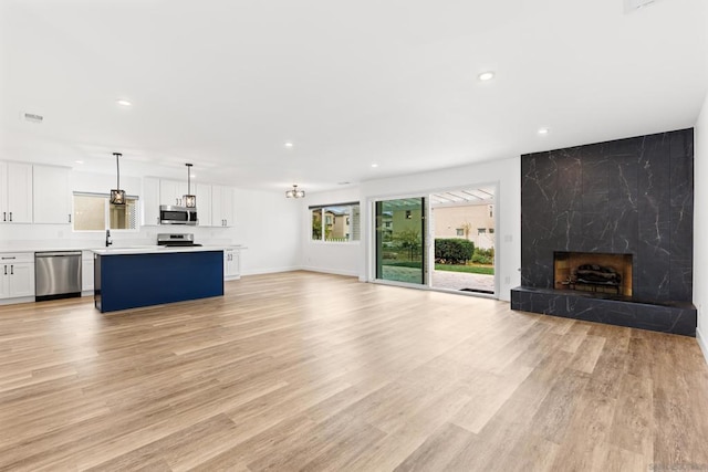 unfurnished living room featuring a premium fireplace, sink, and light wood-type flooring