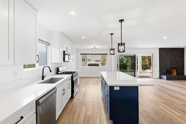 kitchen featuring sink, blue cabinetry, white cabinets, and appliances with stainless steel finishes