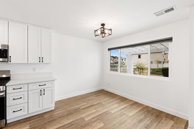 unfurnished dining area with a chandelier and light wood-type flooring