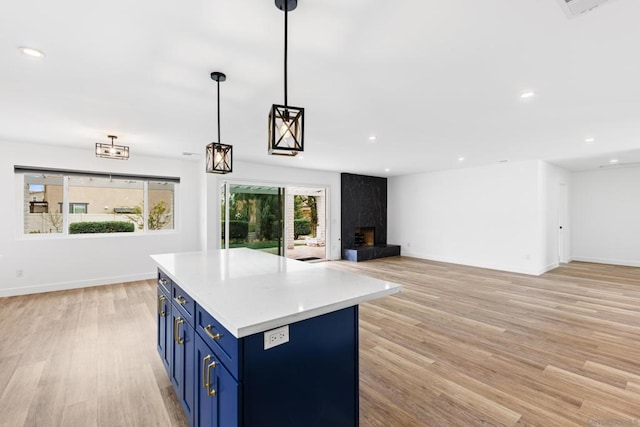 kitchen featuring blue cabinetry, plenty of natural light, a fireplace, and hanging light fixtures