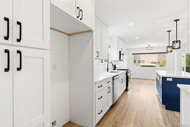 kitchen with decorative light fixtures, sink, white cabinets, light hardwood / wood-style floors, and stainless steel appliances