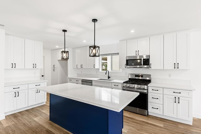 kitchen featuring sink, stainless steel appliances, white cabinets, a kitchen island, and decorative light fixtures