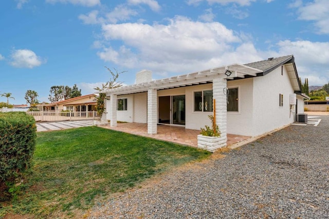 rear view of house with central AC unit, a lawn, and a patio