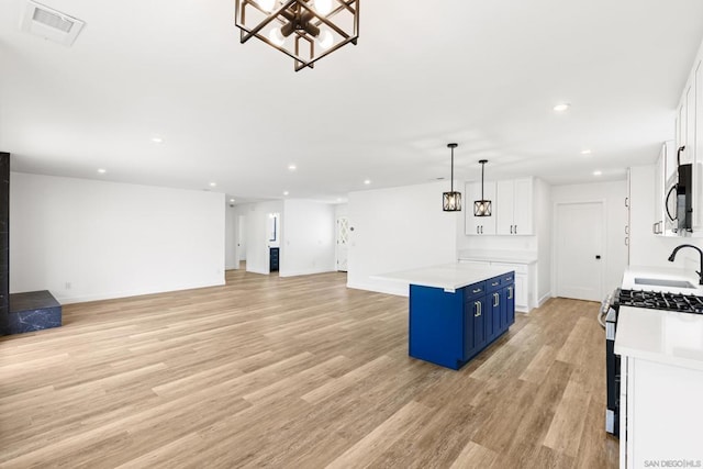 kitchen with blue cabinets, appliances with stainless steel finishes, pendant lighting, and white cabinets