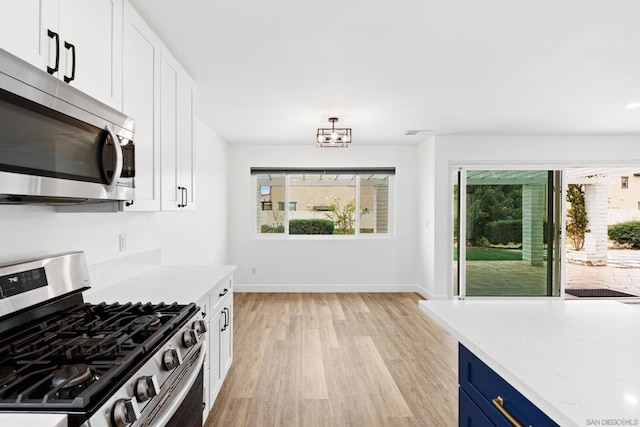 kitchen with blue cabinetry, white cabinetry, light wood-type flooring, stainless steel appliances, and light stone countertops