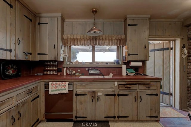 kitchen featuring sink, wooden walls, dishwashing machine, pendant lighting, and decorative backsplash