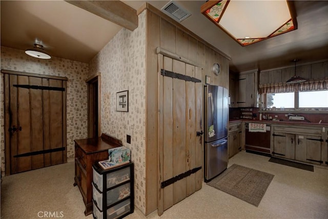 kitchen featuring vaulted ceiling with beams, stainless steel refrigerator, and black dishwasher