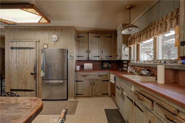 kitchen with tile counters, stainless steel fridge, sink, and tasteful backsplash