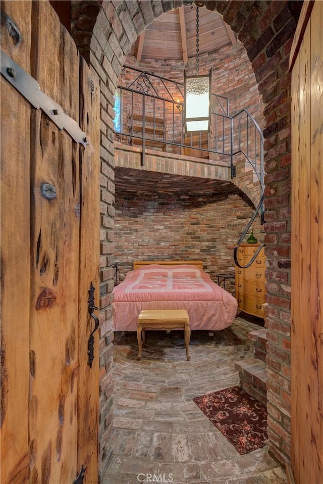 bathroom with brick wall and high vaulted ceiling