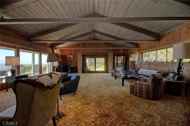 living room with vaulted ceiling with beams, a wealth of natural light, carpet, and wood walls