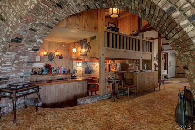 interior space with a towering ceiling, brick ceiling, brick wall, and wood walls