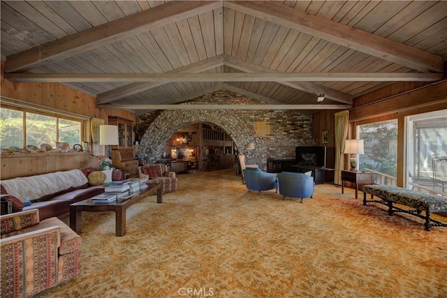 carpeted living room with lofted ceiling with beams, wooden ceiling, and wood walls