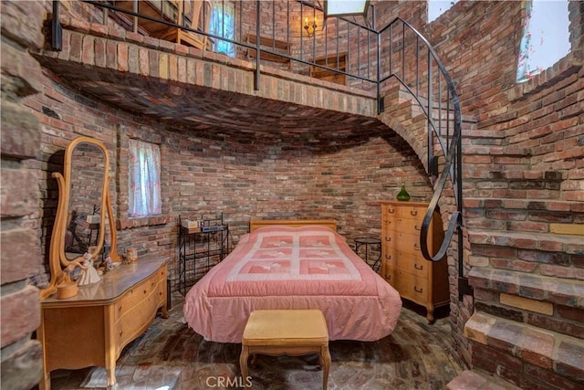 interior space featuring hardwood / wood-style flooring, brick wall, and a towering ceiling