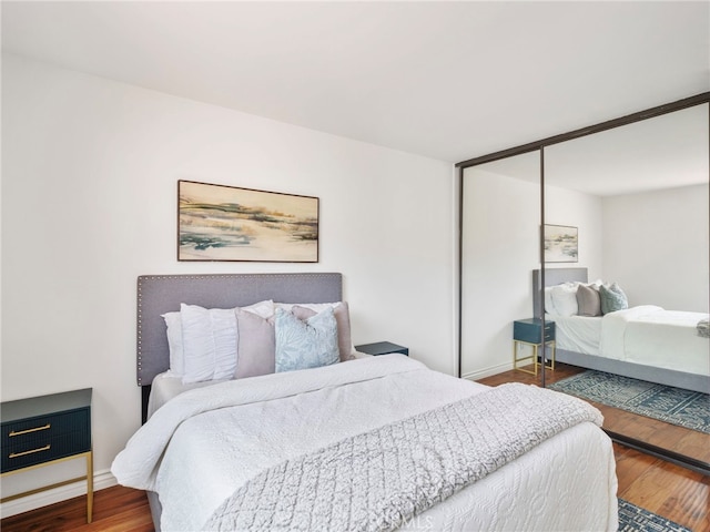 bedroom with dark wood-type flooring and a closet