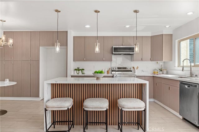 kitchen with stainless steel appliances, a center island, sink, and decorative light fixtures