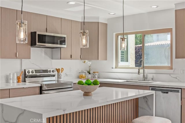 kitchen featuring sink, appliances with stainless steel finishes, hanging light fixtures, light stone counters, and light brown cabinets