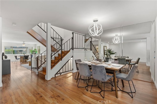 dining space featuring ceiling fan with notable chandelier and light wood-type flooring