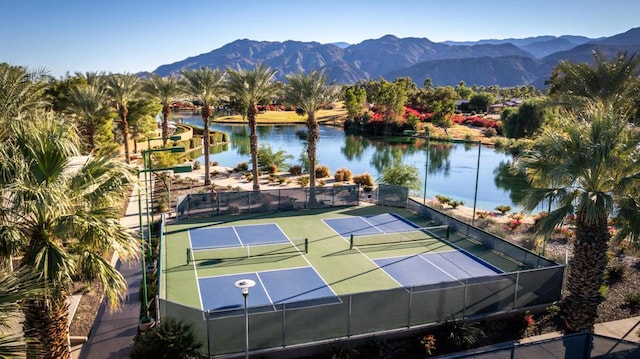 view of tennis court featuring a water and mountain view