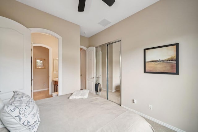 carpeted bedroom featuring ensuite bathroom, ceiling fan, and a closet