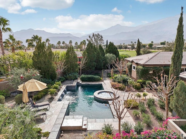 view of swimming pool with an in ground hot tub, pool water feature, a mountain view, and a patio area