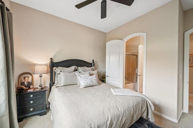 bedroom featuring ceiling fan, light colored carpet, and ensuite bath